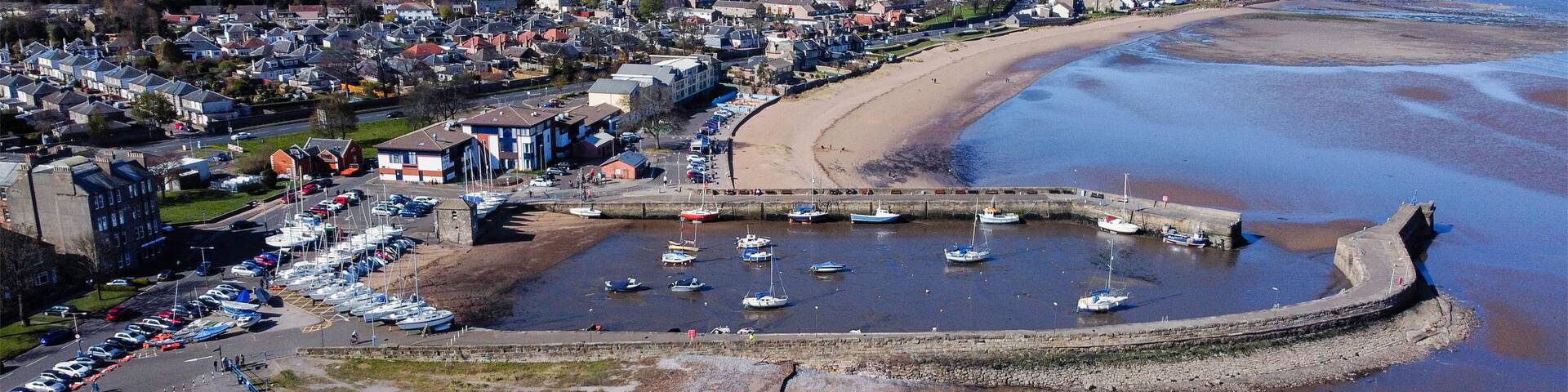 A coastal town with a marina, sandy beach, and residential buildings.