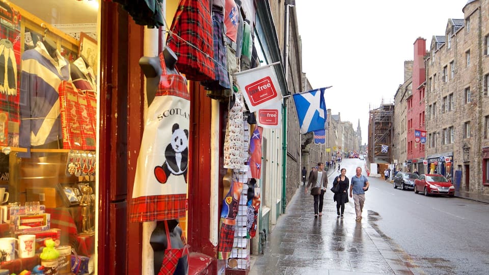En våd gade i en historisk by med butikker og flag.