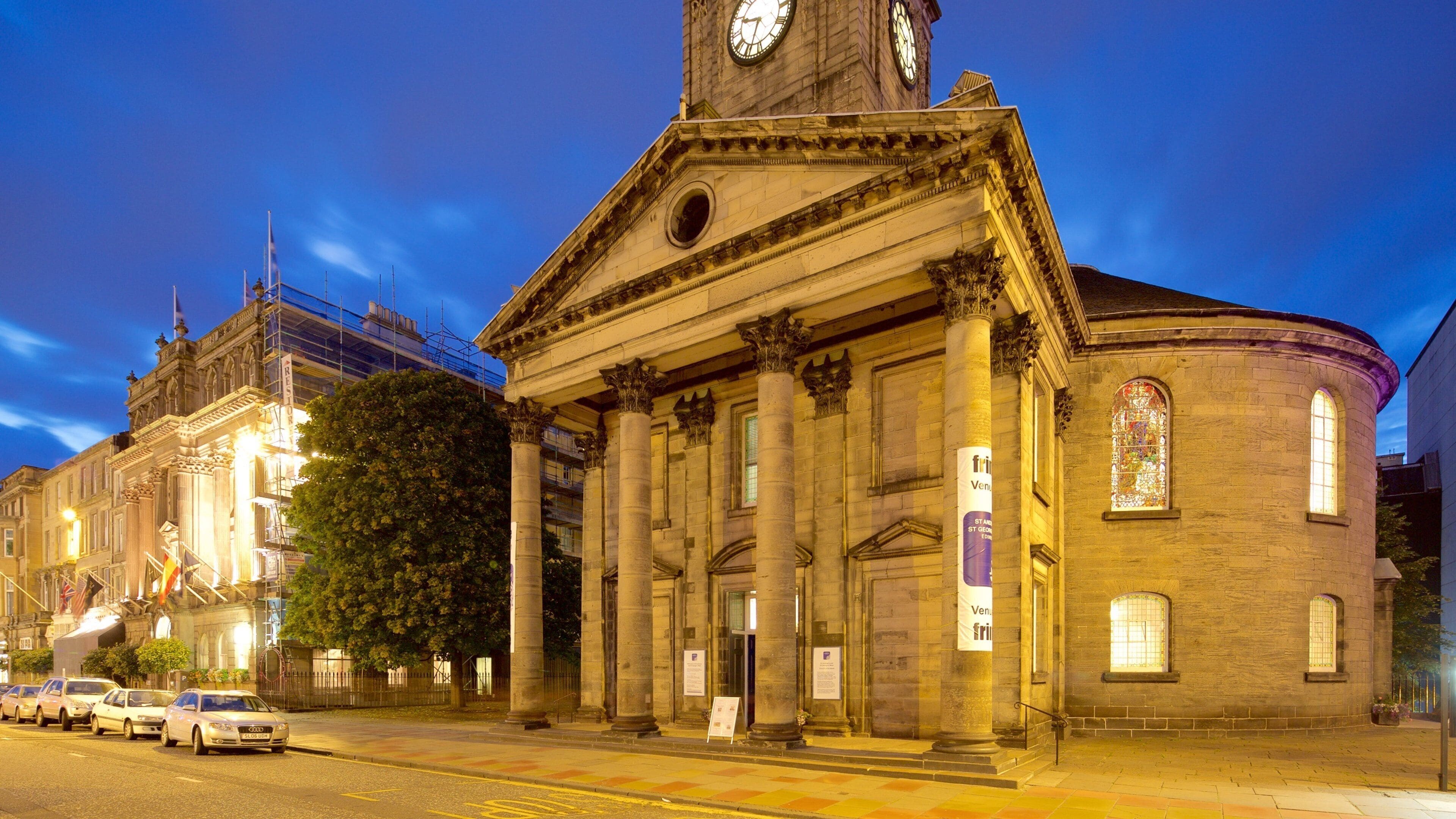 A historic building with a clock tower, columns, and a large tree in front.