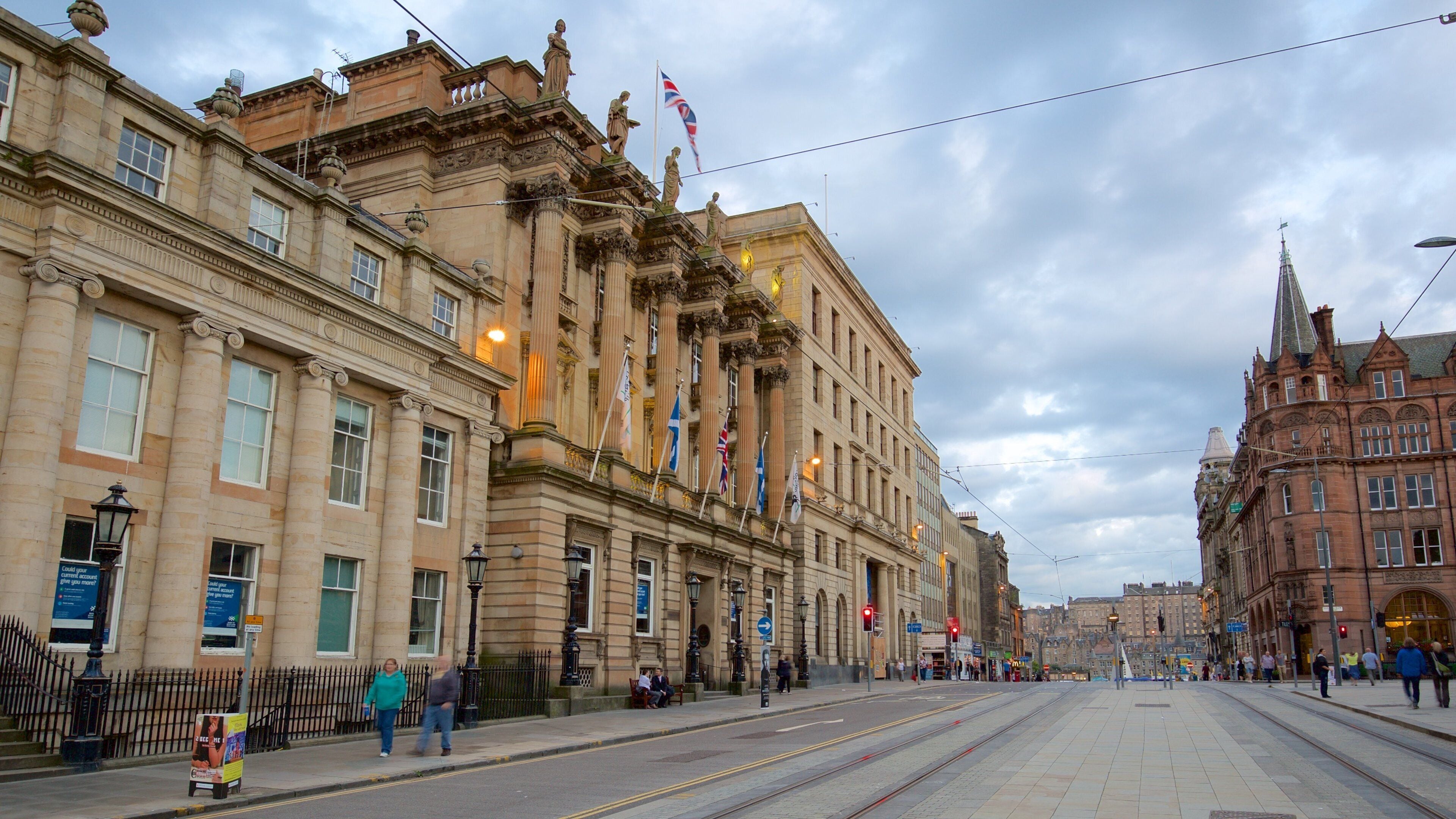 Un edificio storico con architettura elaborata, bandiere e binari del tram.