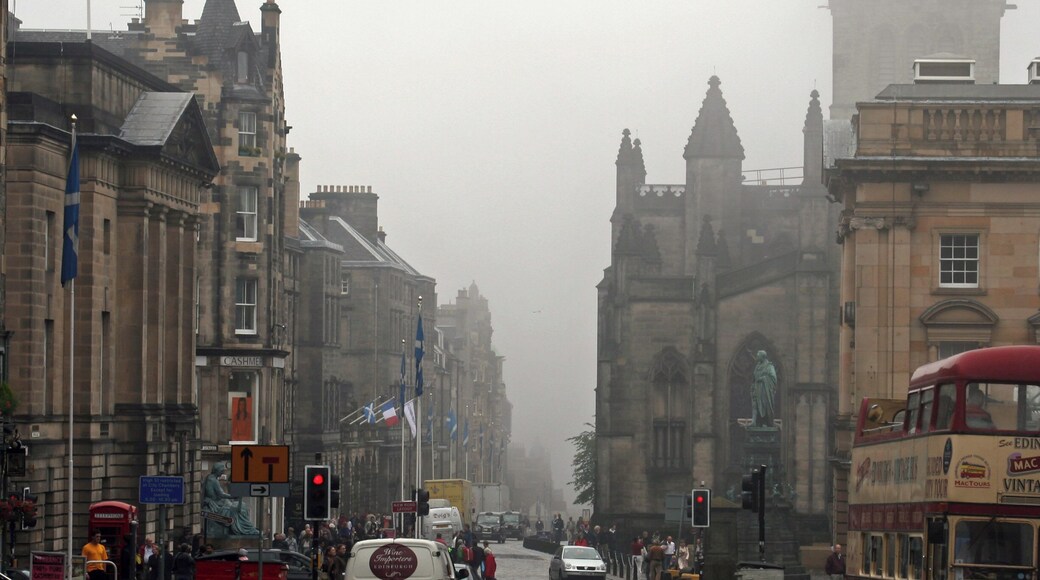 A view down the High Street (part of the Royal Mile) in Edinburgh, with St. Giles cathedral on the right hand side. A Lothian Buses Mac Tours tour bus, an open top Routemaster, passes on the right.