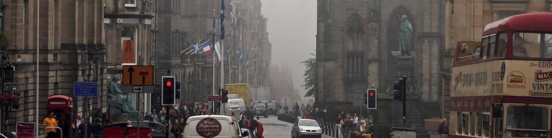 A view down the High Street (part of the Royal Mile) in Edinburgh, with St. Giles cathedral on the right hand side. A Lothian Buses Mac Tours tour bus, an open top Routemaster, passes on the right.
