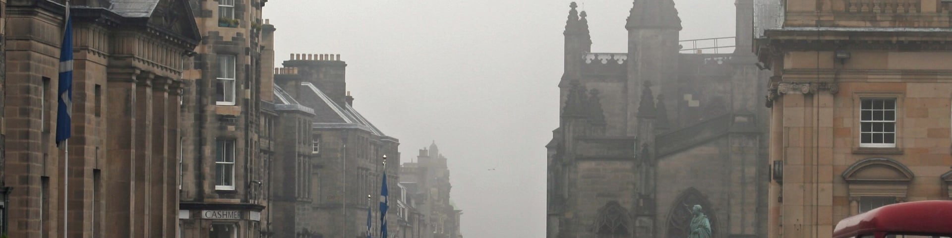 A view down the High Street (part of the Royal Mile) in Edinburgh, with St. Giles cathedral on the right hand side. A Lothian Buses Mac Tours tour bus, an open top Routemaster, passes on the right.