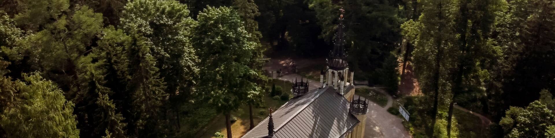 An aerial view of a church surrounded by dense forest.
