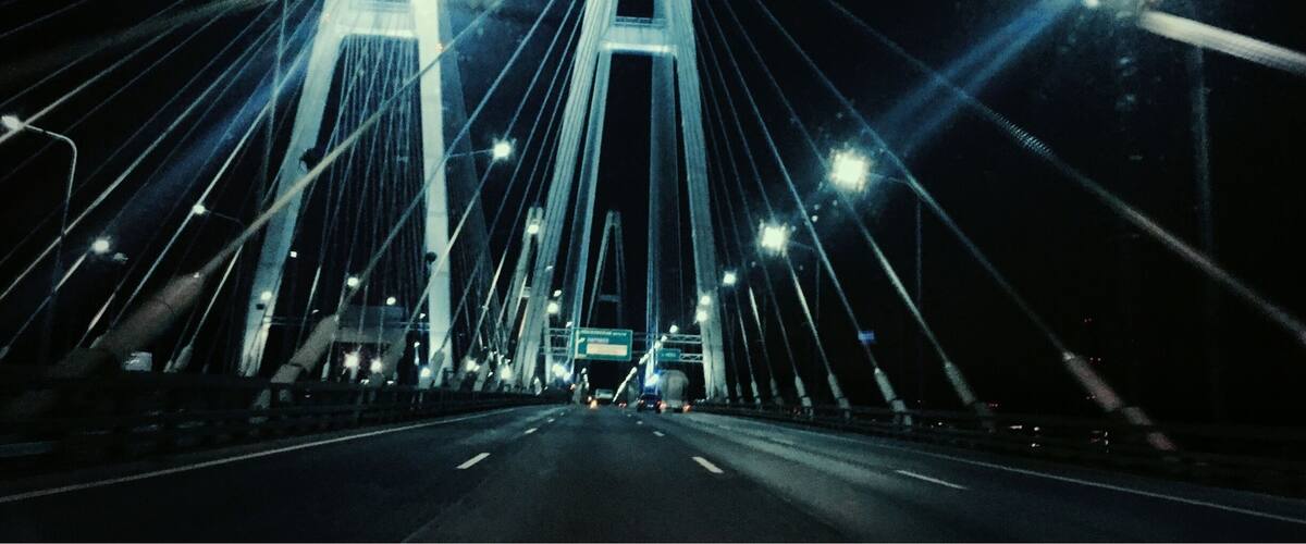 A nighttime view of a large suspension bridge with illuminated cables and roadways.