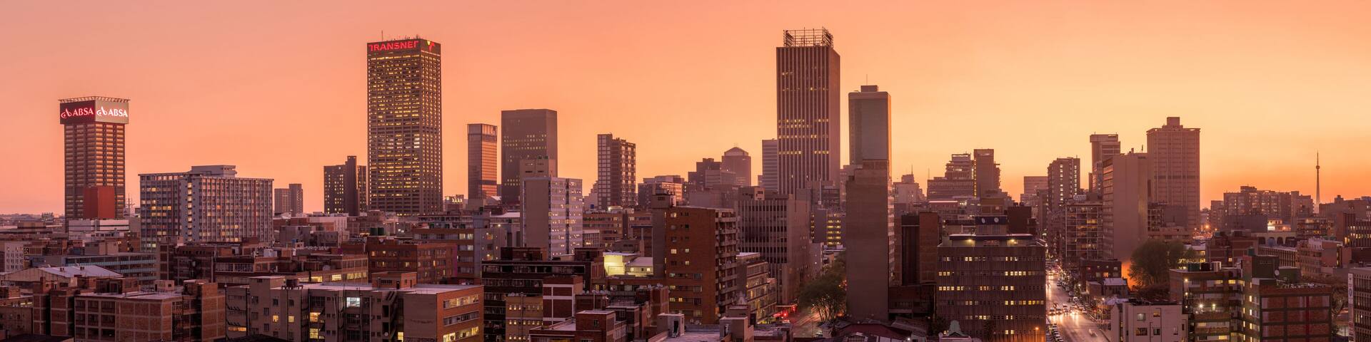 A beautiful and dramatic panoramic photograph of the Johannesburg city skyline, taken on a golden evening after sunset.