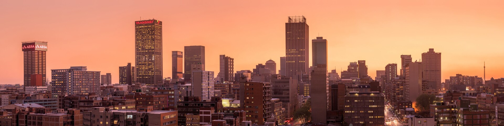 A beautiful and dramatic panoramic photograph of the Johannesburg city skyline, taken on a golden evening after sunset.