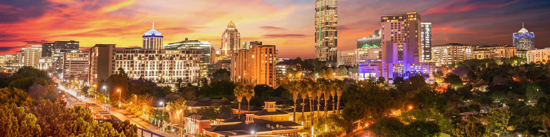 A city skyline at night with illuminated buildings and a starry sky.