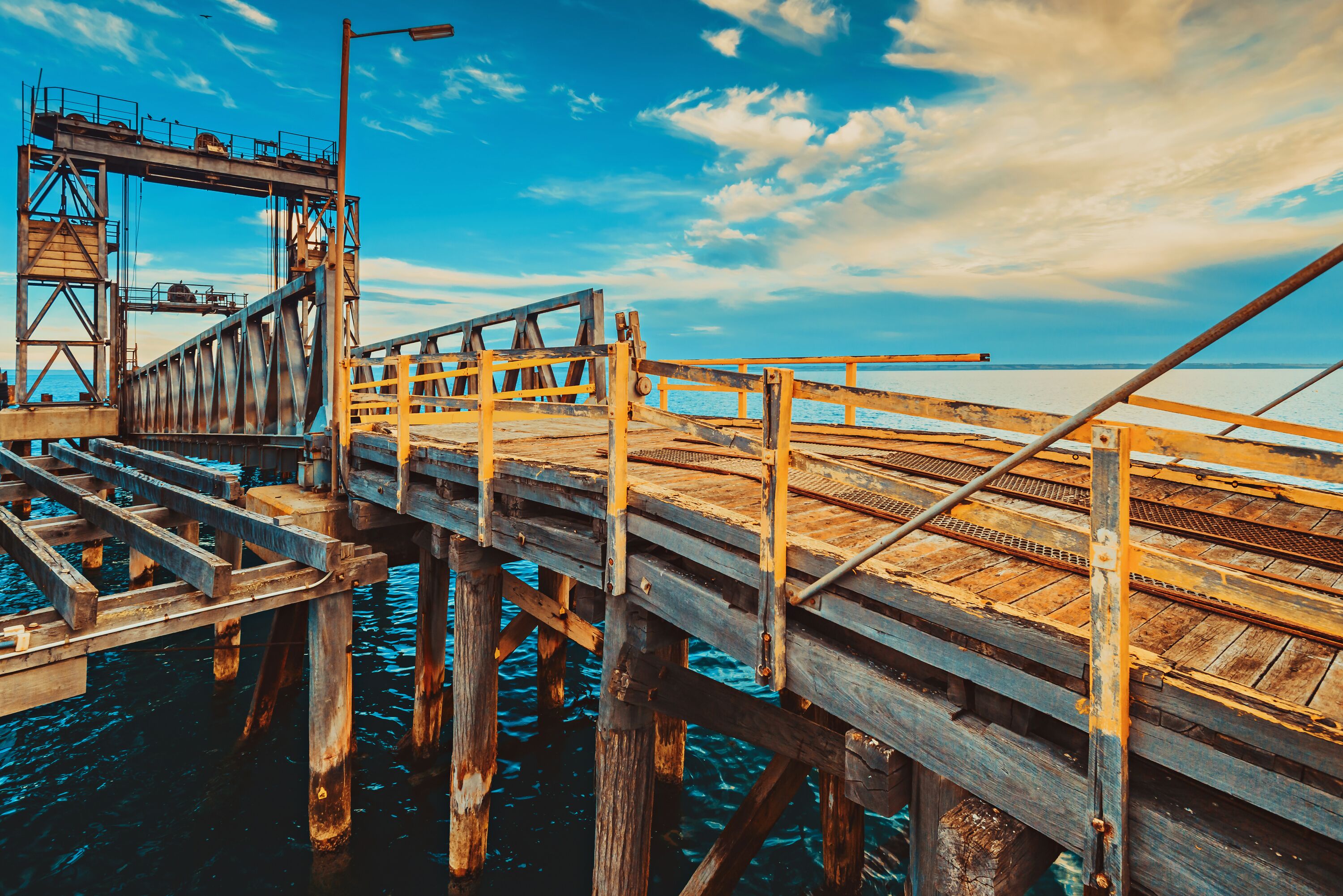 A wooden pier extending into a body of water with a clear sky above.
