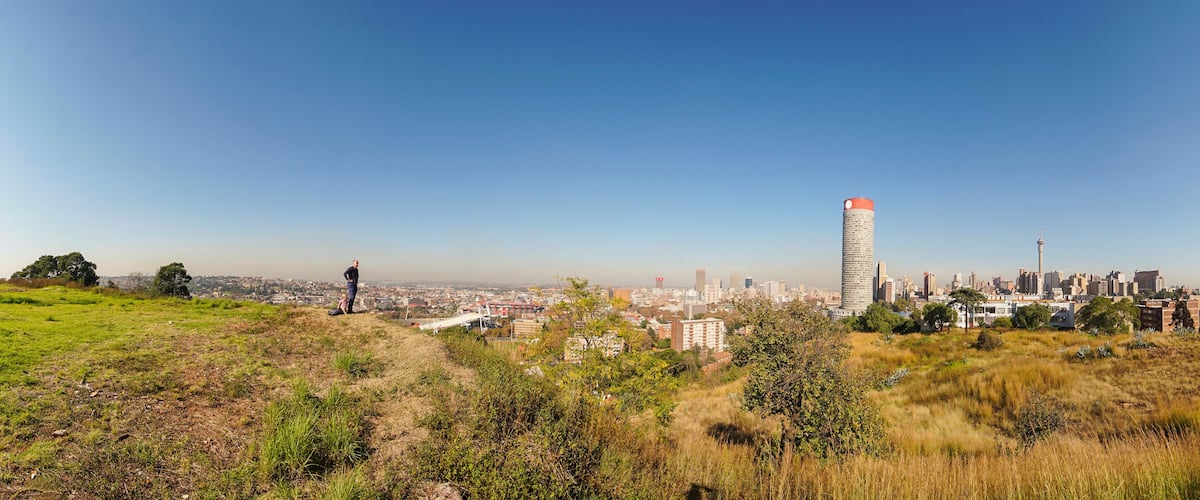 Une vue urbaine avec une tour imposante et une colline verdoyante au premier plan.