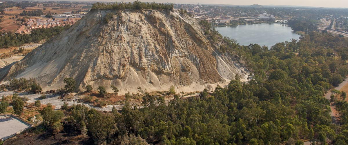 Une grande montagne aux pentes abruptes, dont le sommet est couvert de forêt et au pied de laquelle coule une rivière.