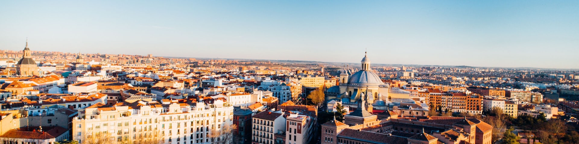 Vista panorâmica de uma paisagem urbana com uma cúpula imponente, edifícios urbanos densos e céu azul límpido.
