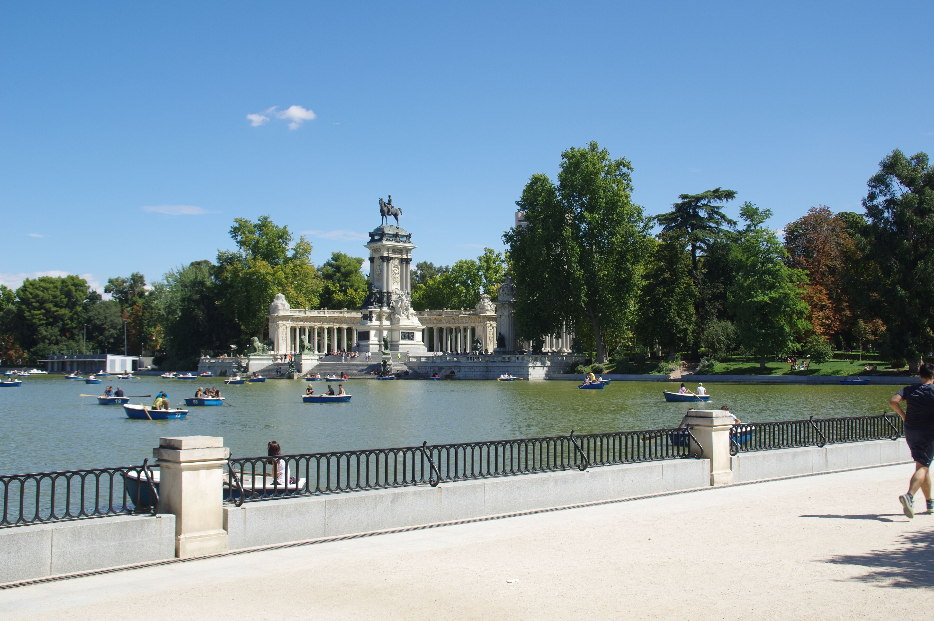 A river with boats, a statue, and a park with trees.