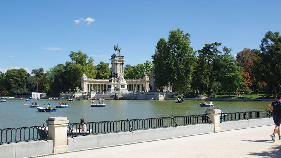 A river with boats, a statue, and a park with trees.