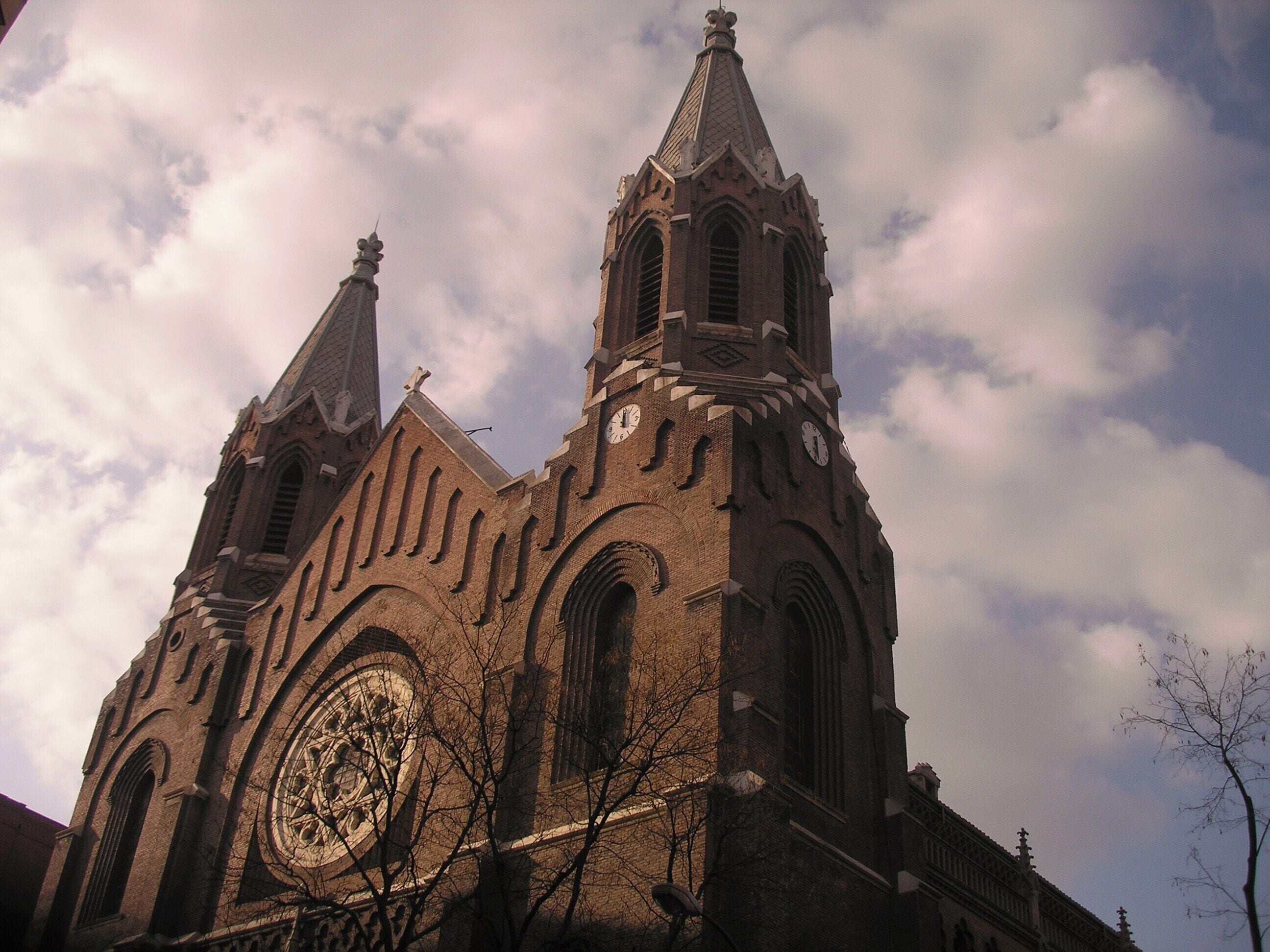 Una iglesia grande con una torre del reloj destacada y un amplio ventanal circular.
