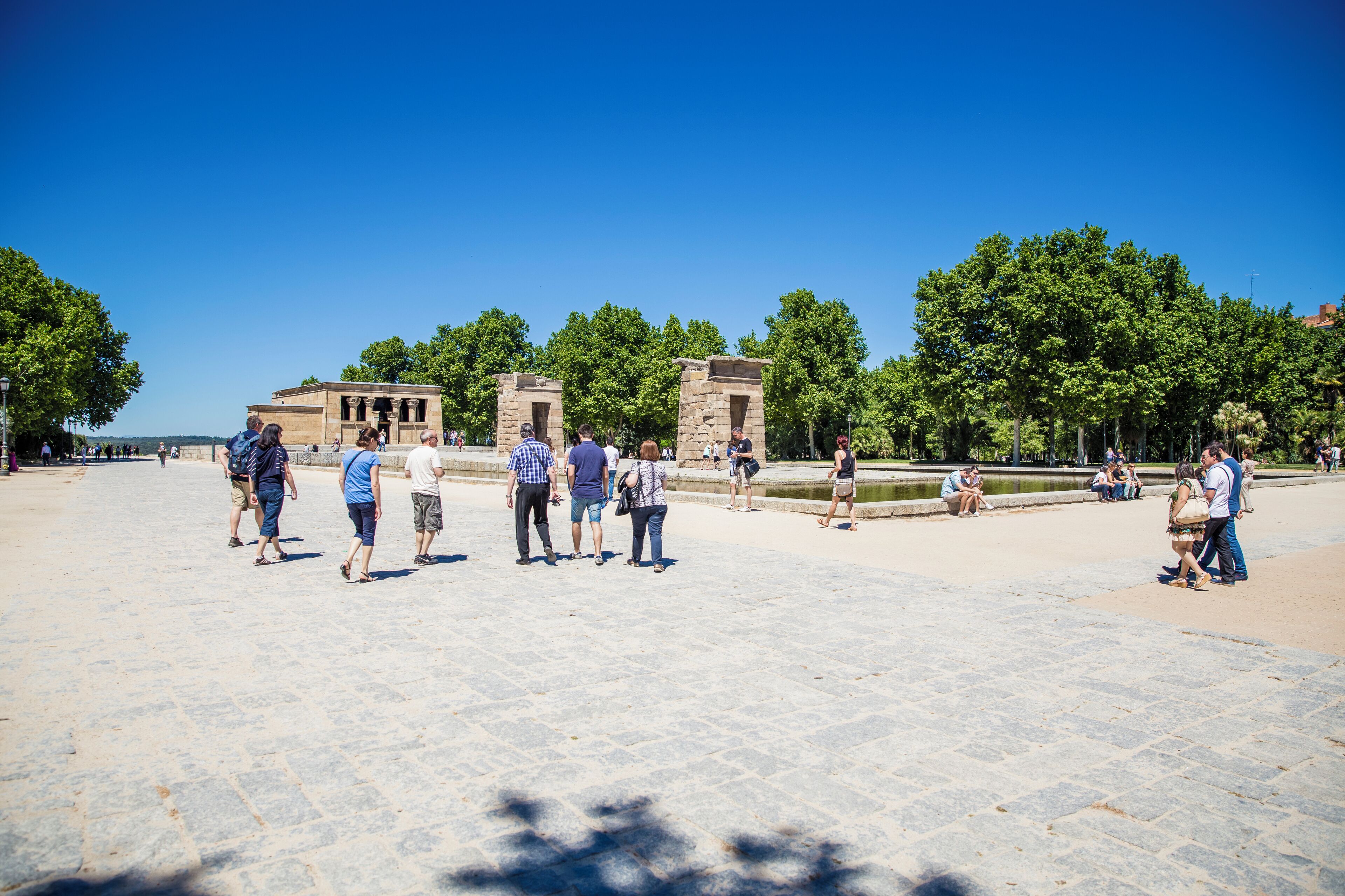 A historical plaza with stone buildings and a fountain.