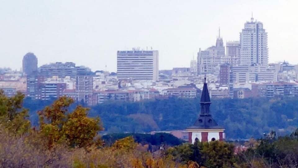 A cityscape with a prominent church steeple and modern buildings in the background.