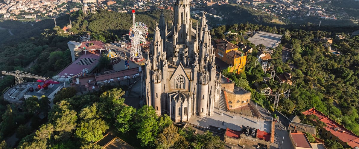 Una catedral con una aguja alta, rodeada por una ciudad densamente poblada y zonas verdes.