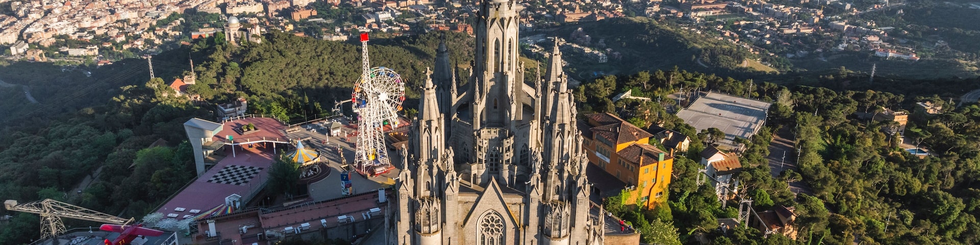 A cathedral with a tall spire, surrounded by a densely populated cityscape and greenery.