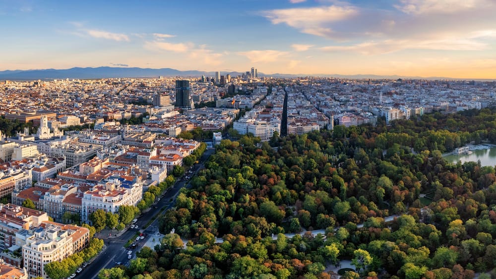 Ein weiter Blick über eine Stadt mit dicht bebautem Stadtgebiet, einem Fluss und einem großen Park mit Herbstlaub.
