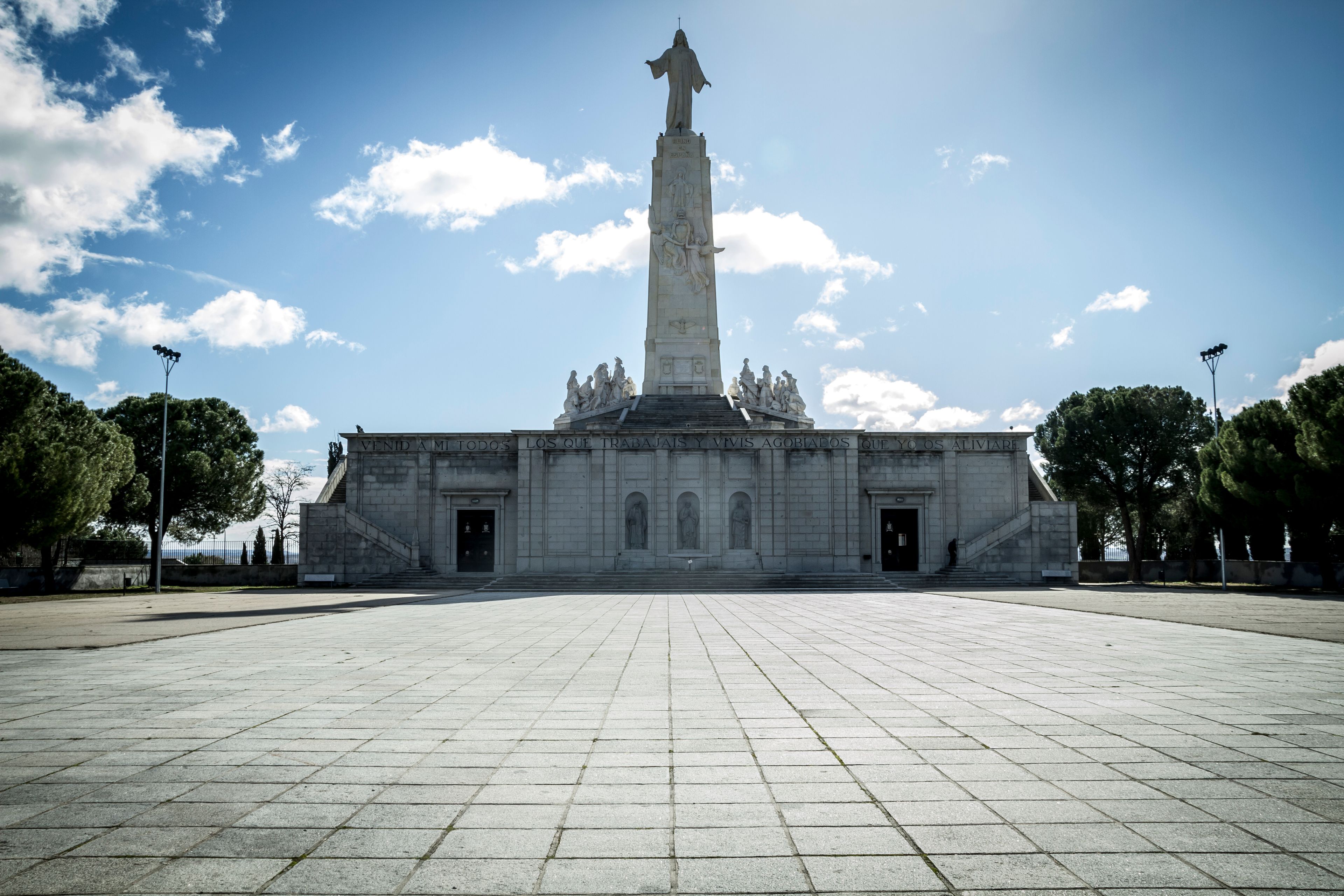 A large, open plaza with a tall monument featuring statues at the top.