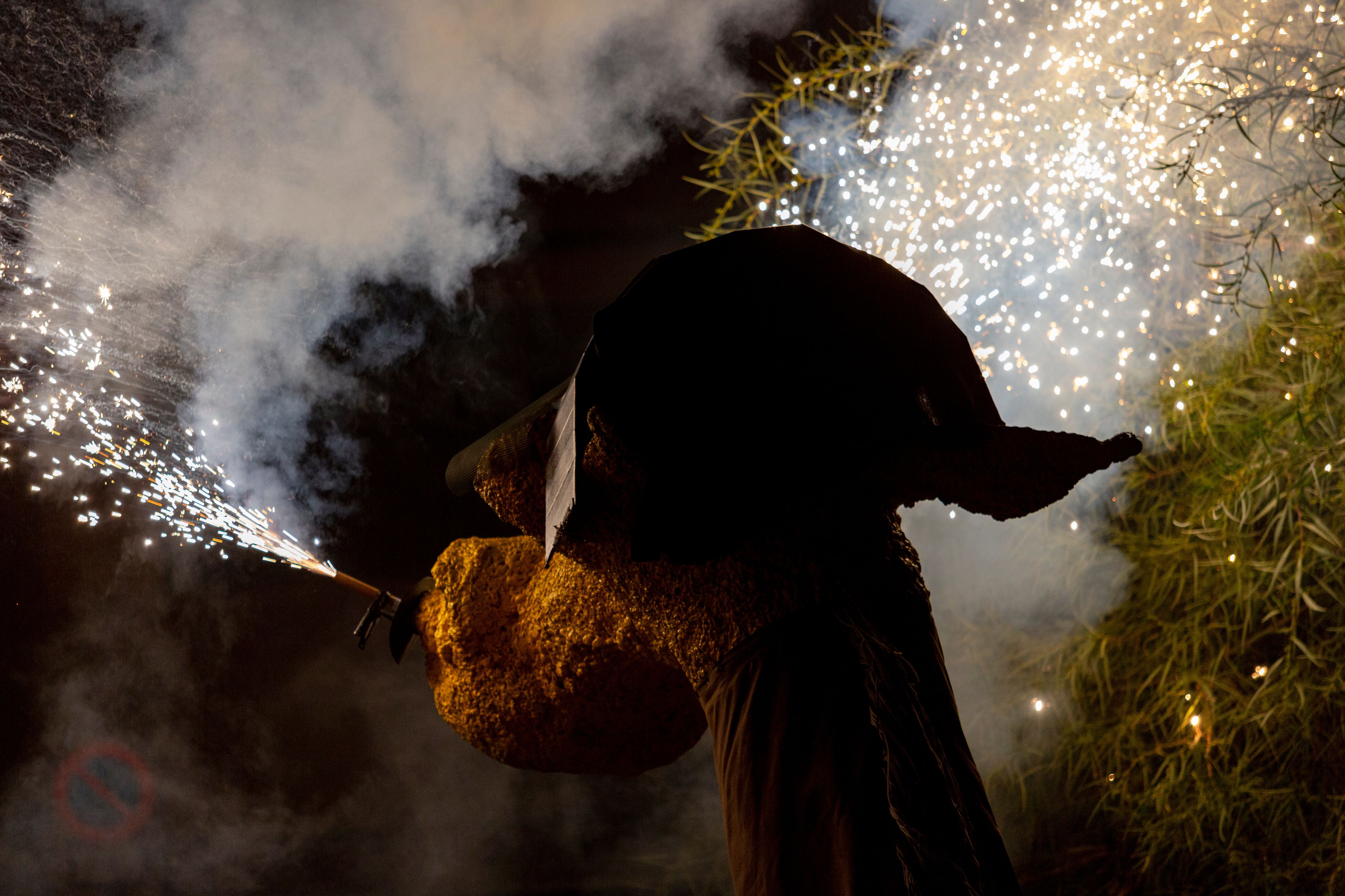 A statue of a person with a hat, holding a torch, and surrounded by fireworks.