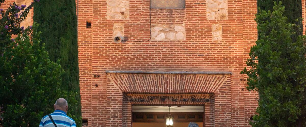 A brick building with a large arched entrance and a crown symbol above it.