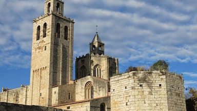 Una fortaleza de piedra histórica, con una torre principal y una torre campanario más pequeña, rodeada por un muro de piedra.
