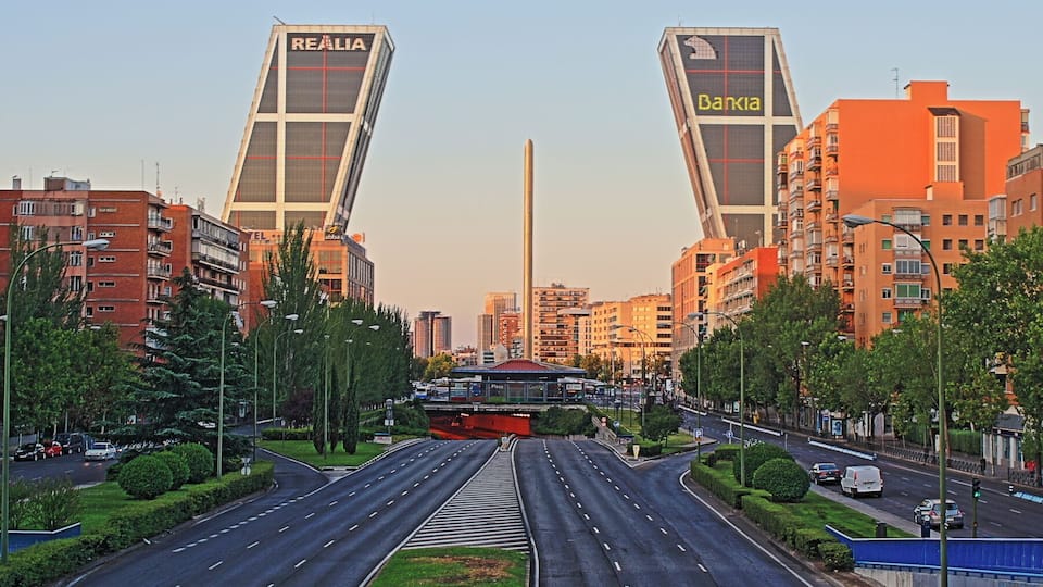 A cityscape with two prominent buildings labeled 'REALIA' and 'Bankia', a wide road with multiple lanes, and surrounding residential buildings.