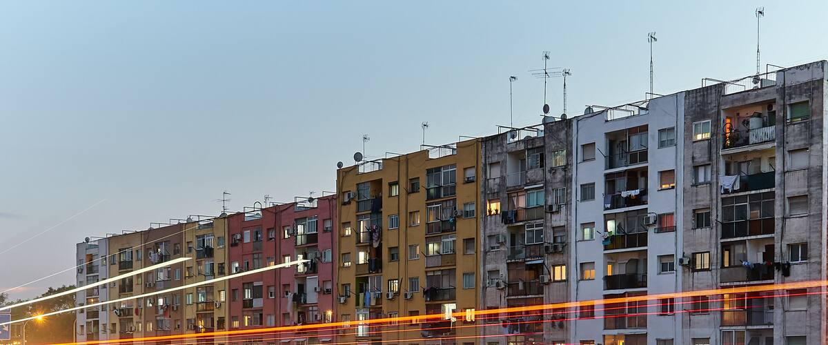 A multi-story residential building complex with balconies and satellite dishes.