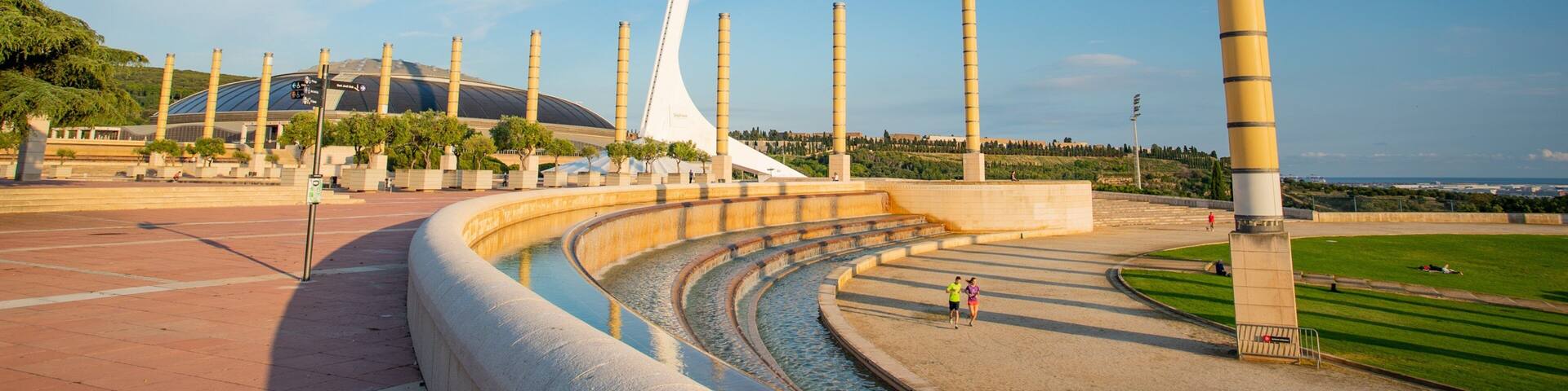 A modern sculpture with a white, spiral design, surrounded by a circular water feature and tall, cylindrical structures.