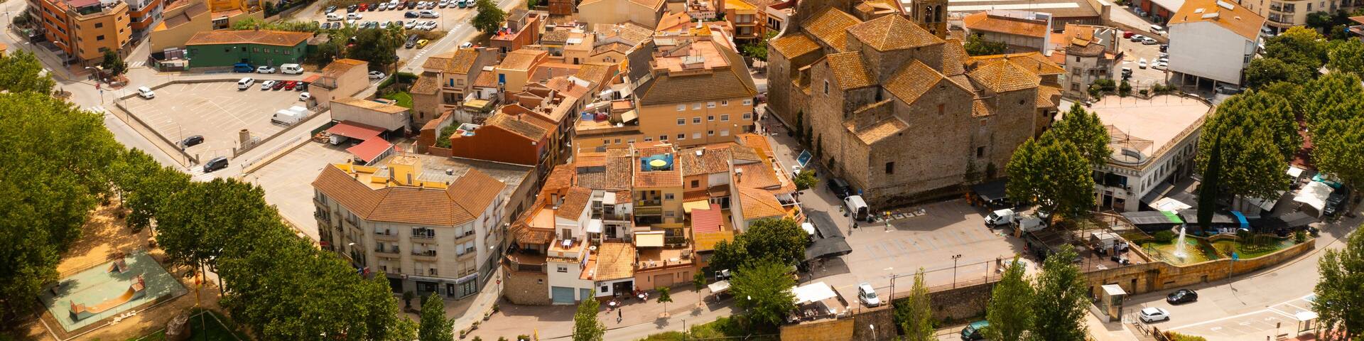 Scenic summer view of tiled roofs of residential houses of Spanish township of Tordera on background of greenery of Montnegre natural park on horizon on sunny day, province of Barcelona, Catalonia