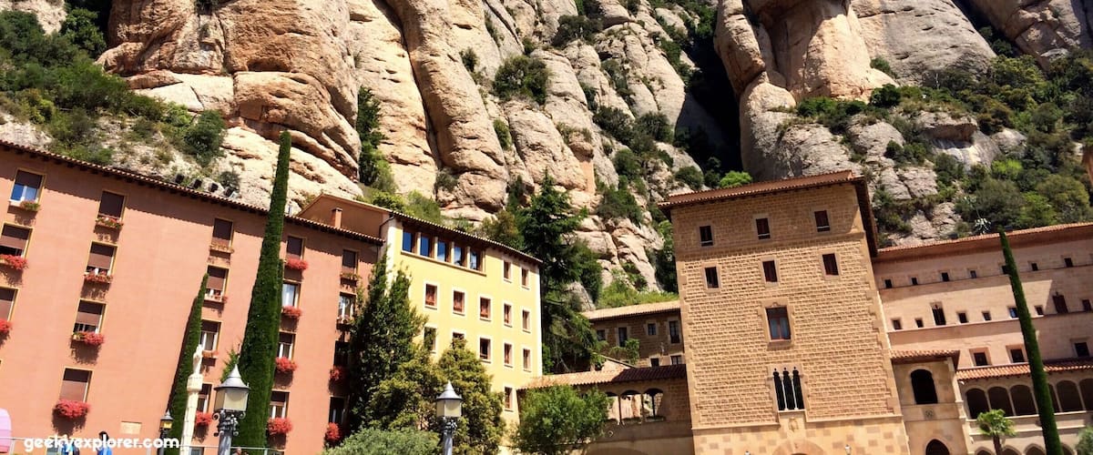 A building with a stone facade, a large rock formation, and a clear blue sky.