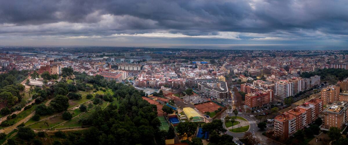 A cityscape with a mix of modern and historic architecture, a large park area, and a cloudy sky.