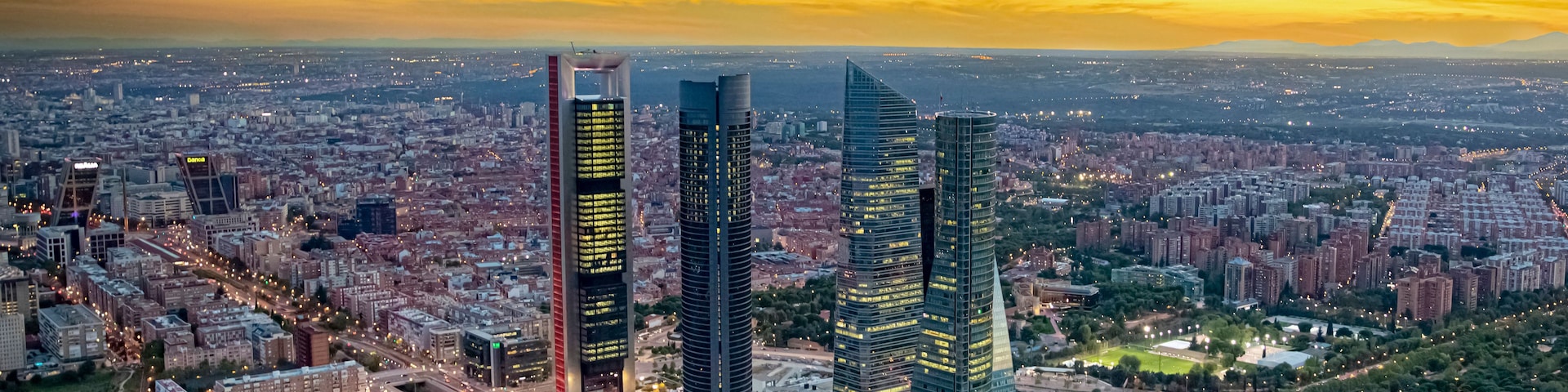 Eine Stadtlandschaft mit markanten Wolkenkratzern, dichter Bebauung und einem Abendhimmel.