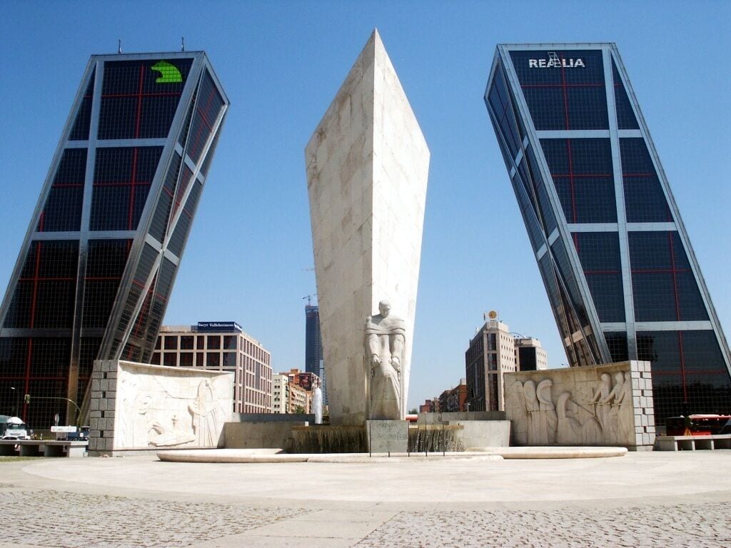A modern plaza with a central monument and two tall buildings with 'REFAELIA' signage.