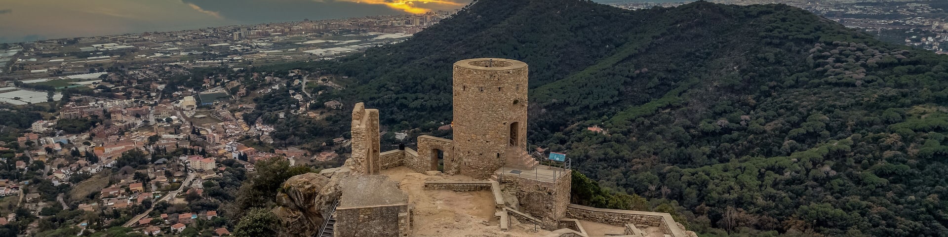 Aerial sunset view of the remains of a small, 11th-century Burriac castle, chapel on a hill, with a modest hike and dramatic views