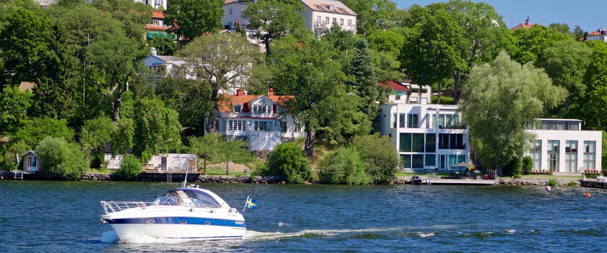 A boat on a lake with houses and trees in the background.