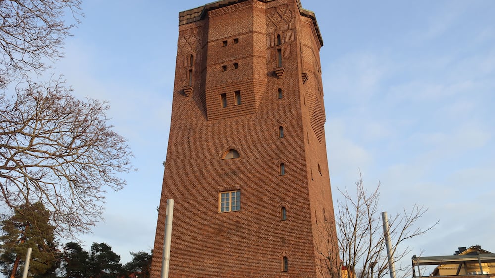 Ein hoher Ziegelturm mit Rundbogenfenstern und flachem Dach.