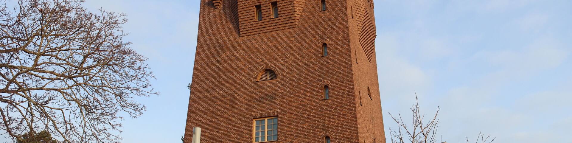 A tall brick tower with arched windows and a flat roof.