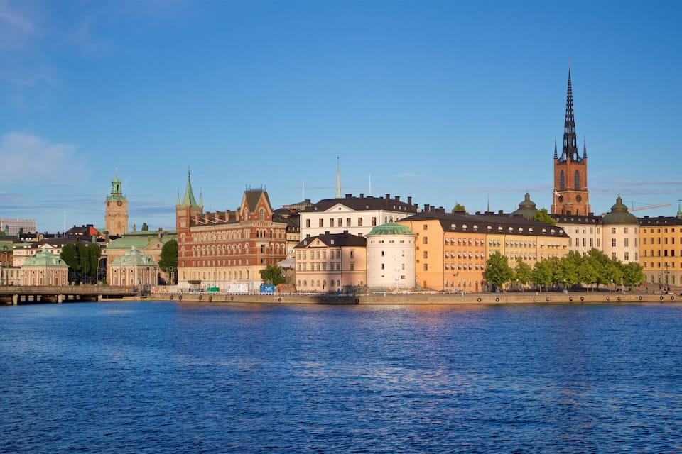 A river with historic buildings and a tall church spire.