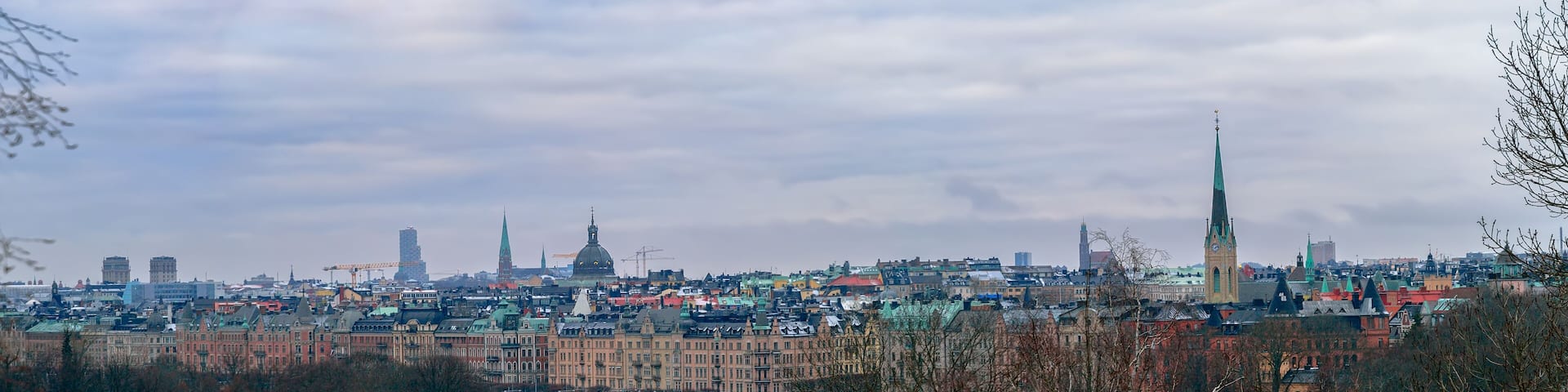 A cityscape with a prominent green spire, a river with bridges, and historic buildings.