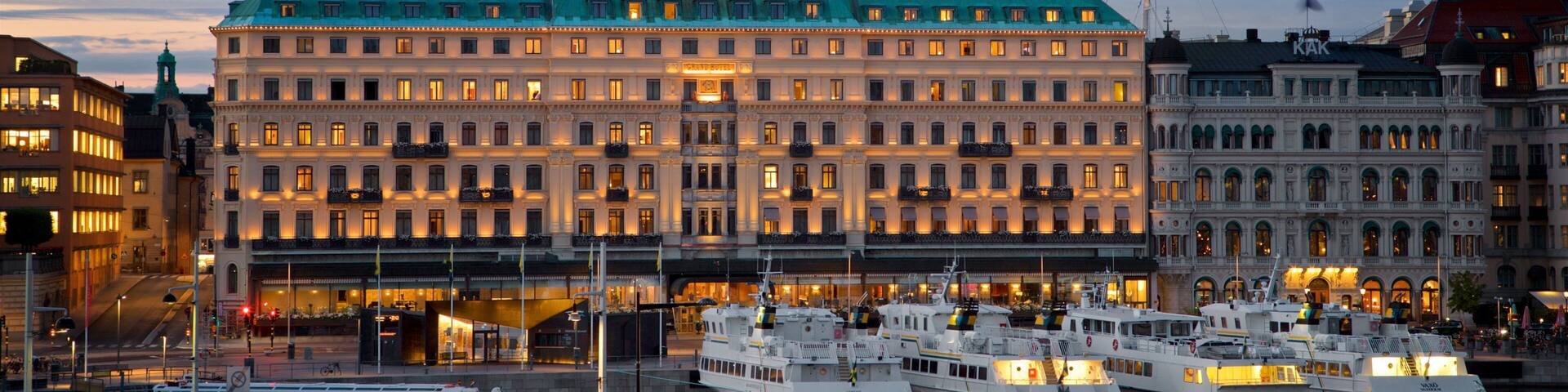 A waterfront with a large hotel and several boats docked.
