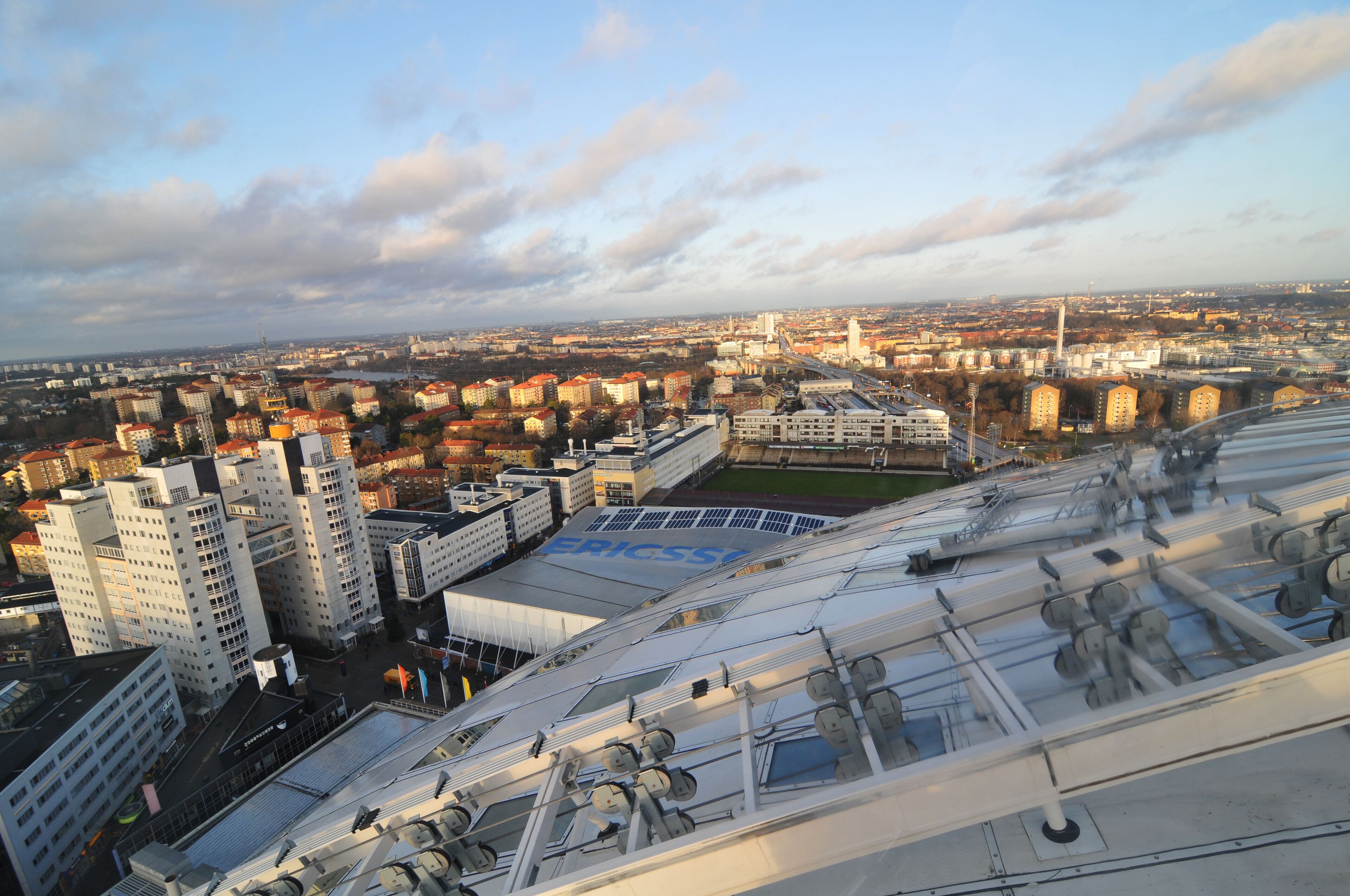 Paisagem urbana com edifícios modernos, um estádio e uma grande ponte.