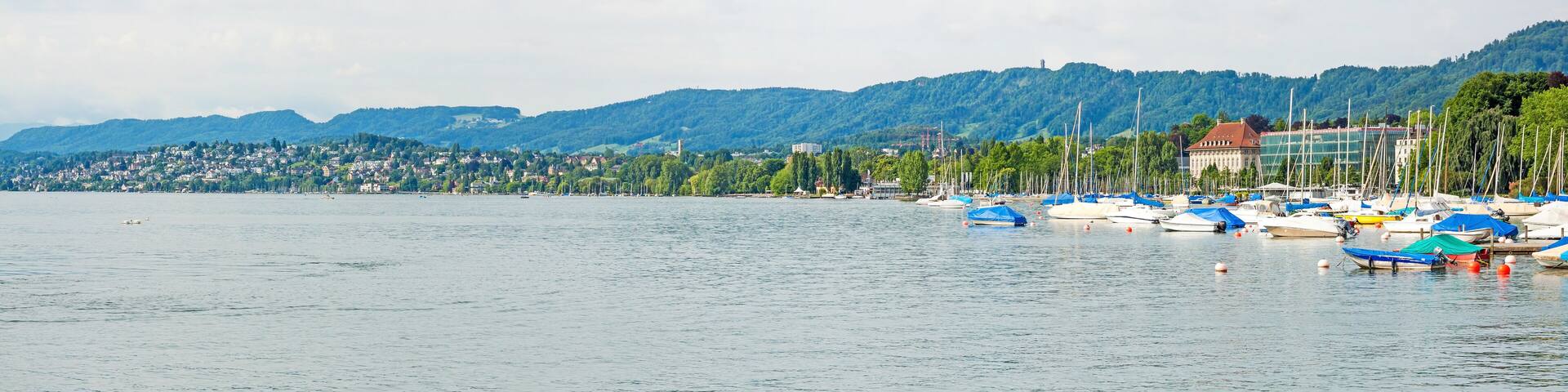 A lake with boats, a town, and mountains in the background.
