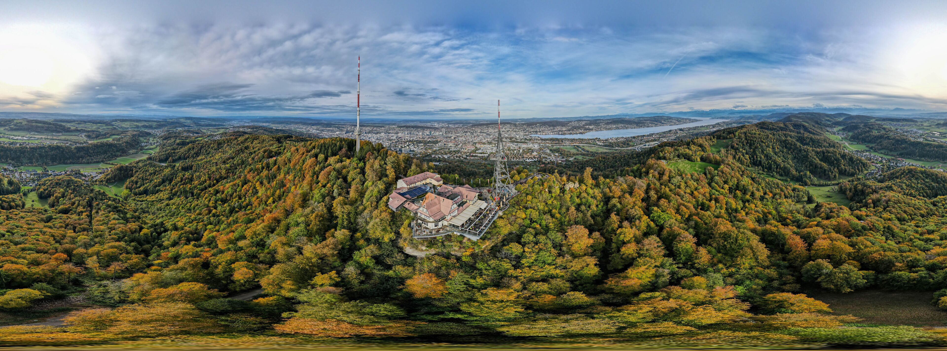 A panoramic view of a valley with a prominent tower, dense forest, and a distant cityscape.