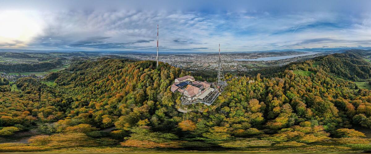 A panoramic view of a valley with a prominent tower, dense forest, and a distant cityscape.