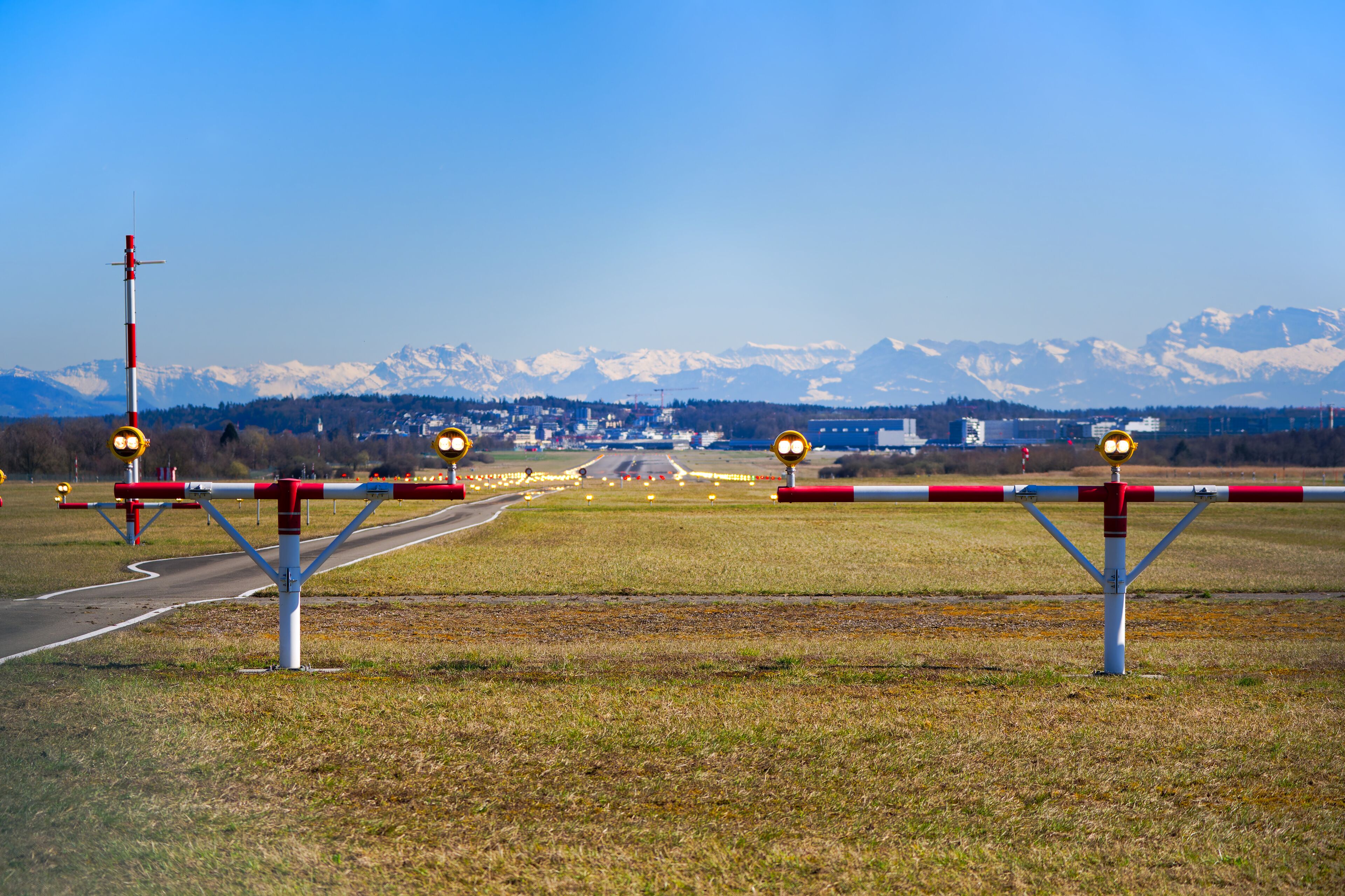 Scenic view of runway number 14 of Swiss Airport Zürich Kloten with beacons and snow covered Swiss Alps in the background on a sunny day. Photo taken March 19th, 2025, Zurich Kloten, Switzerland.