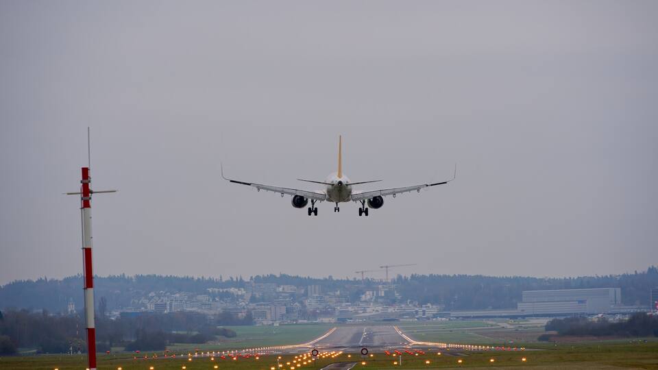 An airplane landing on a runway with city buildings in the background.