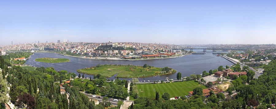 Un río serpentea por una ciudad, con un puente, zonas verdes y edificios históricos.